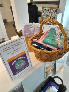 Table in office with a sign for the pyjama drive event and several donated baskets with pyjamas in them